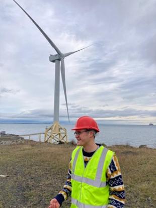 IDCORE Research Engineer, Thomas Page, with a wind turbine in the background